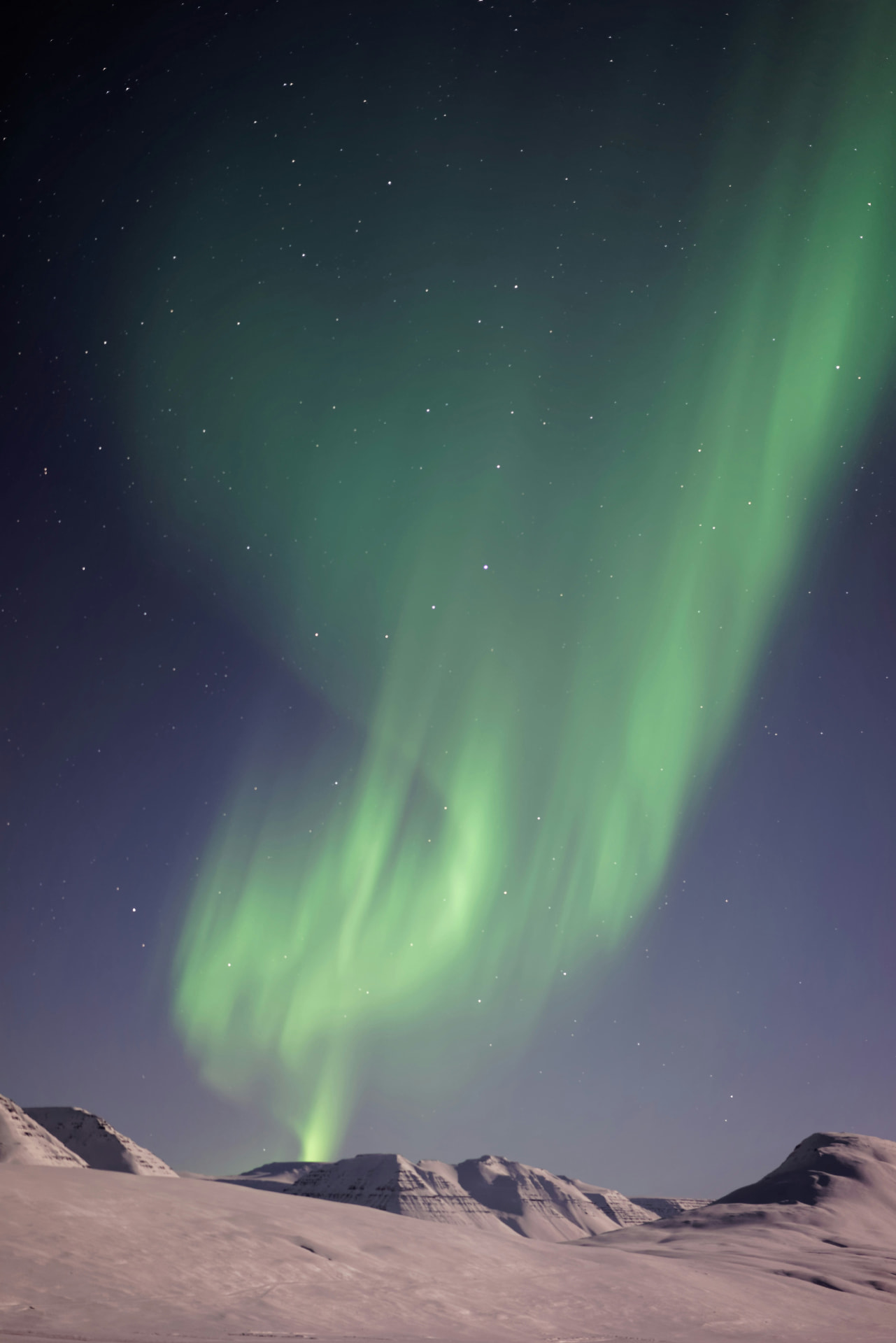Northern lights dancing over a snowy Icelandic mountain landscape